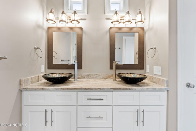 bathroom featuring a chandelier, vanity with extensive cabinet space, and double sink