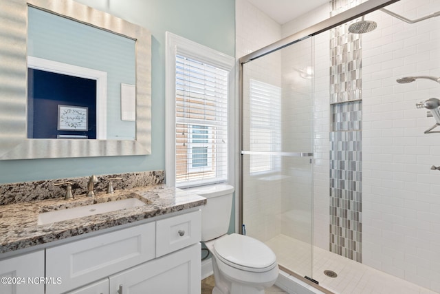 bathroom with a shower with shower door, toilet, and vanity