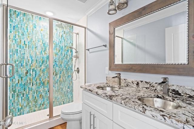 bathroom featuring ornamental molding, a shower with shower door, toilet, and dual vanity