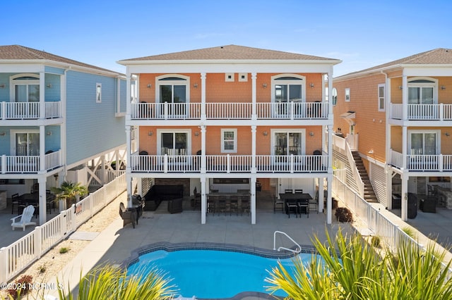 rear view of house featuring a balcony, a fenced in pool, and a patio area