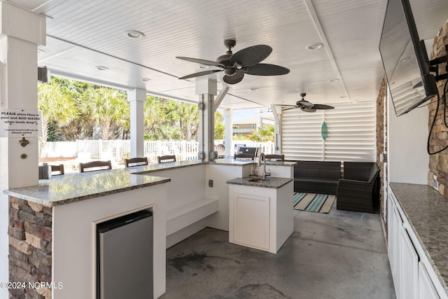 view of patio with exterior kitchen, a bar, and ceiling fan