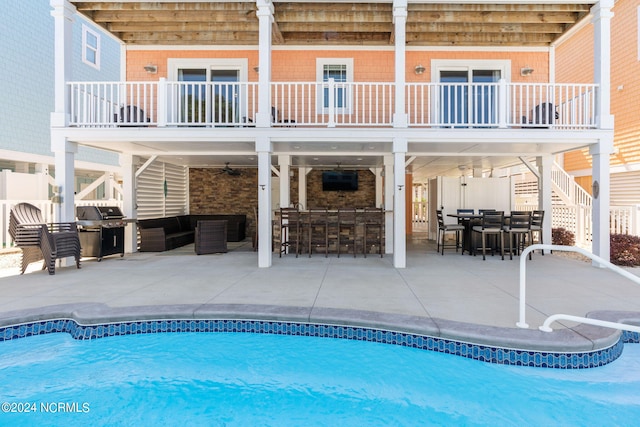 view of swimming pool featuring a patio area, ceiling fan, and a bar