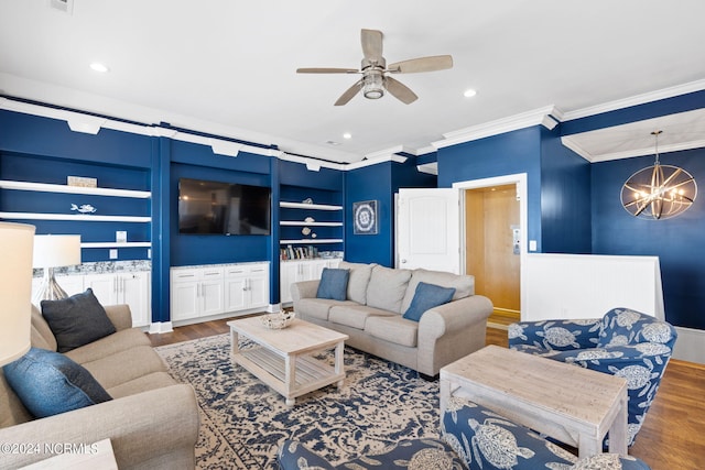 living room featuring wood-type flooring, ceiling fan with notable chandelier, crown molding, and built in features