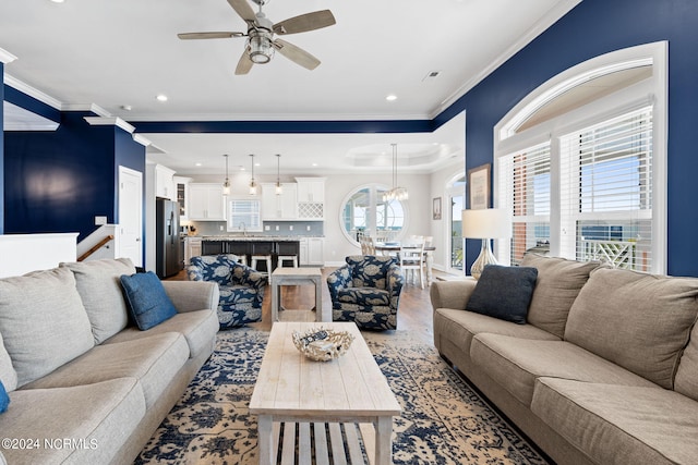 living room featuring ornamental molding, ceiling fan, and sink