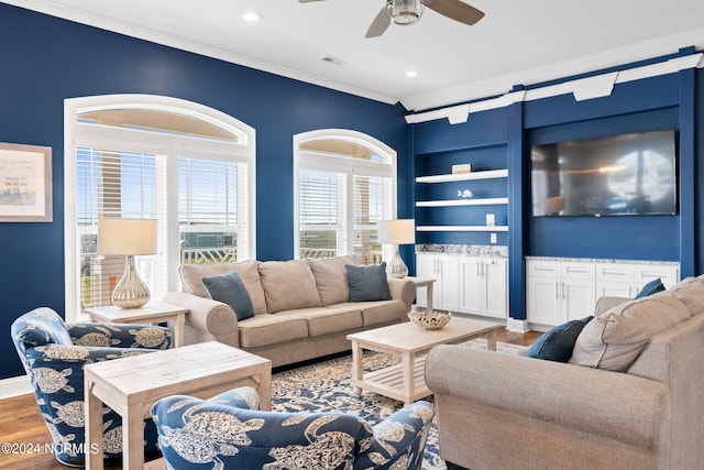 living room with built in features, ceiling fan, crown molding, and hardwood / wood-style flooring