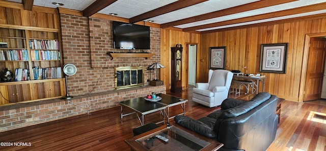 living room featuring wood walls, a brick fireplace, brick wall, beam ceiling, and dark hardwood / wood-style flooring