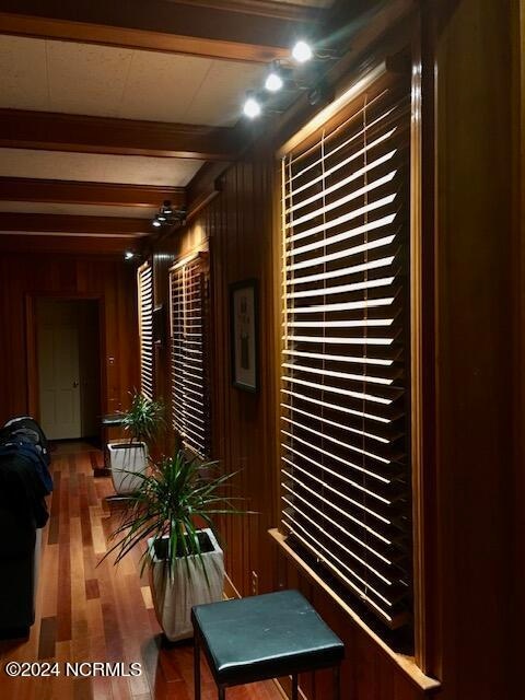 interior space with beam ceiling, wooden walls, and dark hardwood / wood-style floors