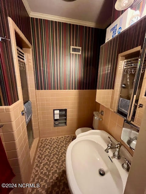 bathroom with tile walls, sink, toilet, tile floors, and a shower