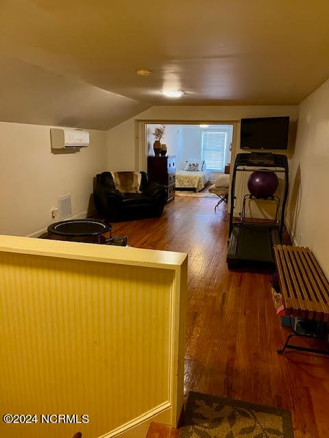 interior space featuring lofted ceiling, a wall unit AC, and hardwood / wood-style flooring