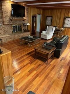 living room with light hardwood / wood-style flooring, wood walls, and a fireplace