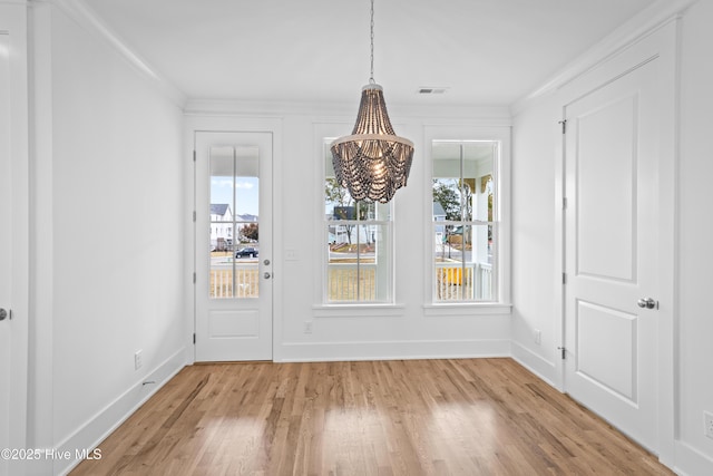 unfurnished dining area with a chandelier, crown molding, and light hardwood / wood-style floors