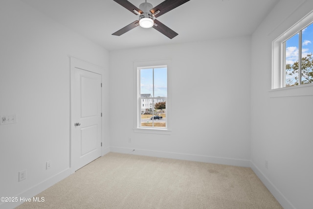 empty room with ceiling fan, plenty of natural light, and light colored carpet