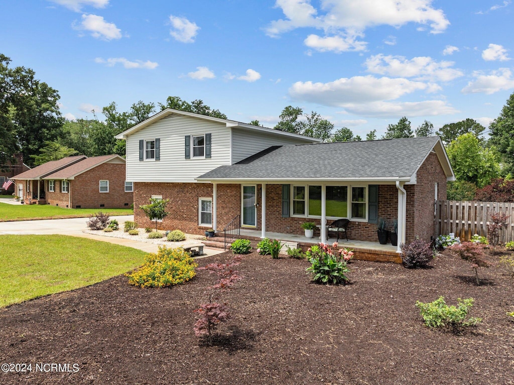 tri-level home featuring covered porch and a front yard