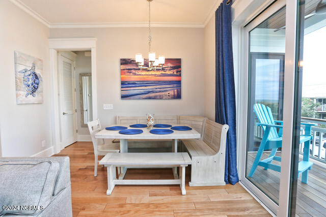 dining space with crown molding, a chandelier, and light wood-type flooring