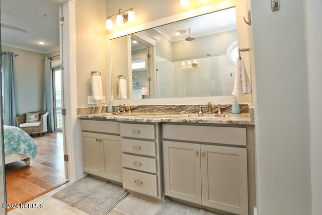 bathroom featuring dual vanity, ornamental molding, and wood-type flooring