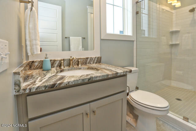 bathroom with a shower with door, toilet, and oversized vanity