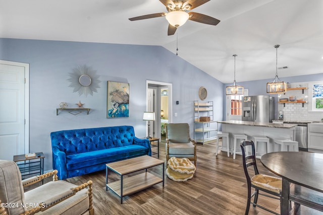 living room with ceiling fan with notable chandelier, vaulted ceiling, and dark wood-type flooring