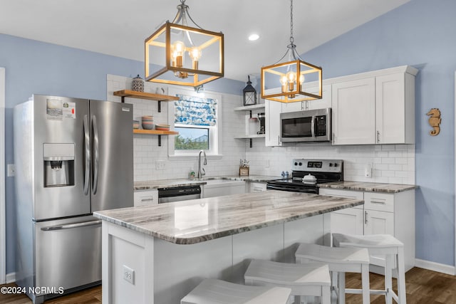 kitchen featuring a center island, backsplash, dark wood-type flooring, decorative light fixtures, and stainless steel appliances