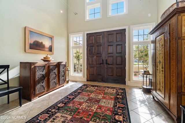 entryway with light tile floors and a towering ceiling