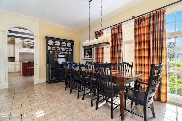 tiled dining room featuring ornamental molding, a notable chandelier, and ornate columns