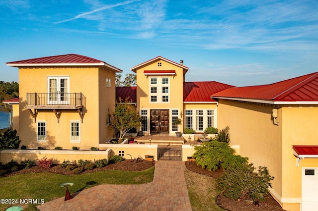 view of front of home with a balcony, a patio, and french doors