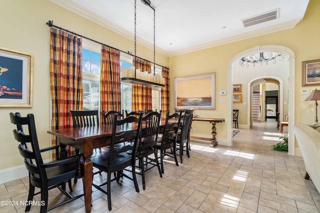 tiled dining space featuring crown molding and a notable chandelier