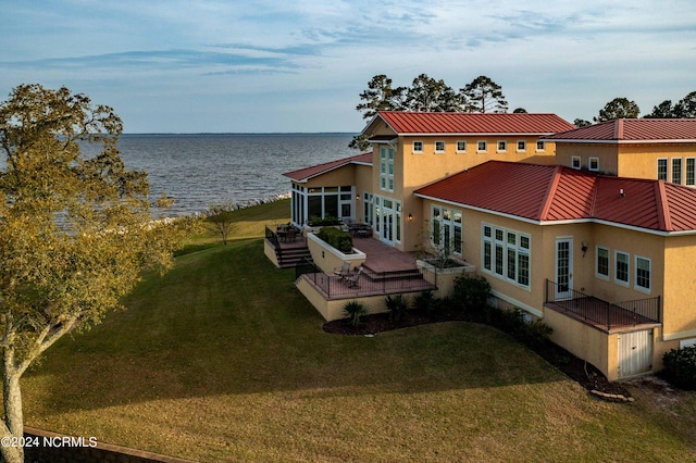 exterior space with a lawn and a deck with water view