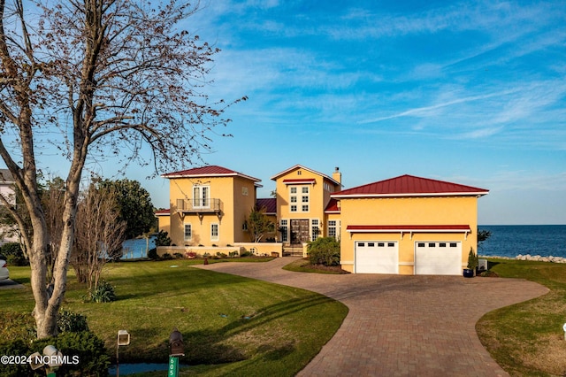 view of front of house featuring a front yard, a water view, a balcony, and a garage