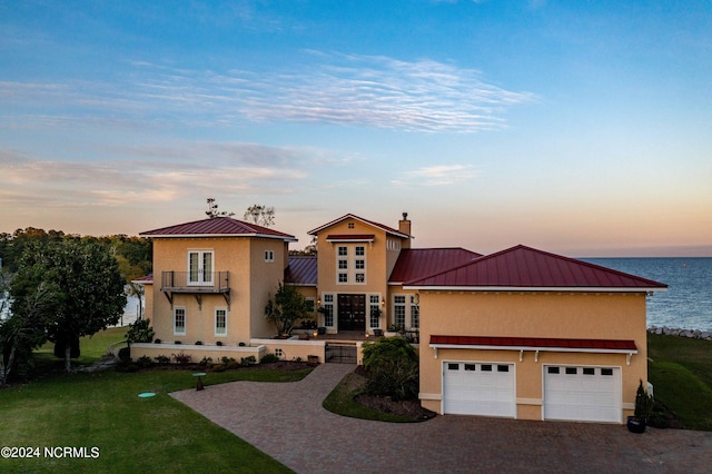 view of front of home with a lawn, a water view, and a garage