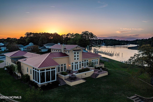 aerial view at dusk featuring a water view