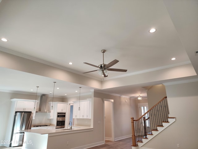 kitchen with wall chimney exhaust hood, kitchen peninsula, decorative light fixtures, white cabinets, and appliances with stainless steel finishes