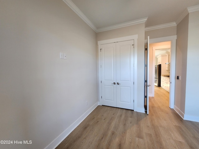 unfurnished bedroom with stainless steel fridge, light hardwood / wood-style floors, crown molding, and a closet