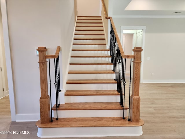 staircase with crown molding and hardwood / wood-style floors