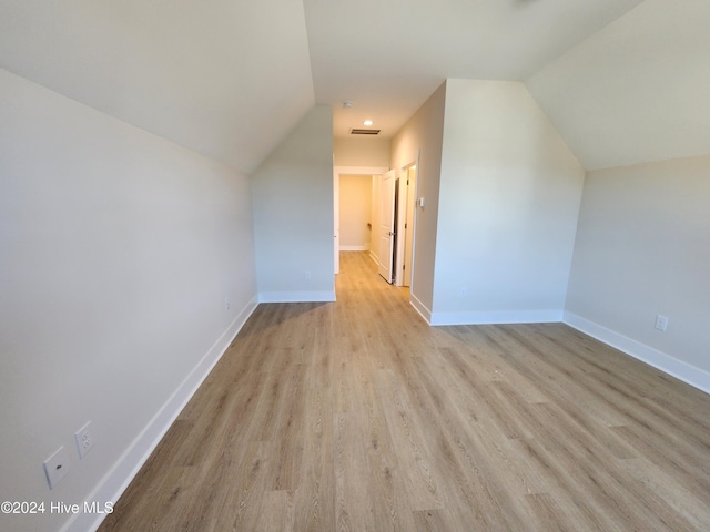 additional living space with light wood-type flooring and vaulted ceiling