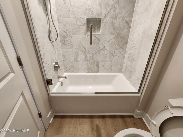 bathroom featuring wood-type flooring, toilet, and tiled shower / bath