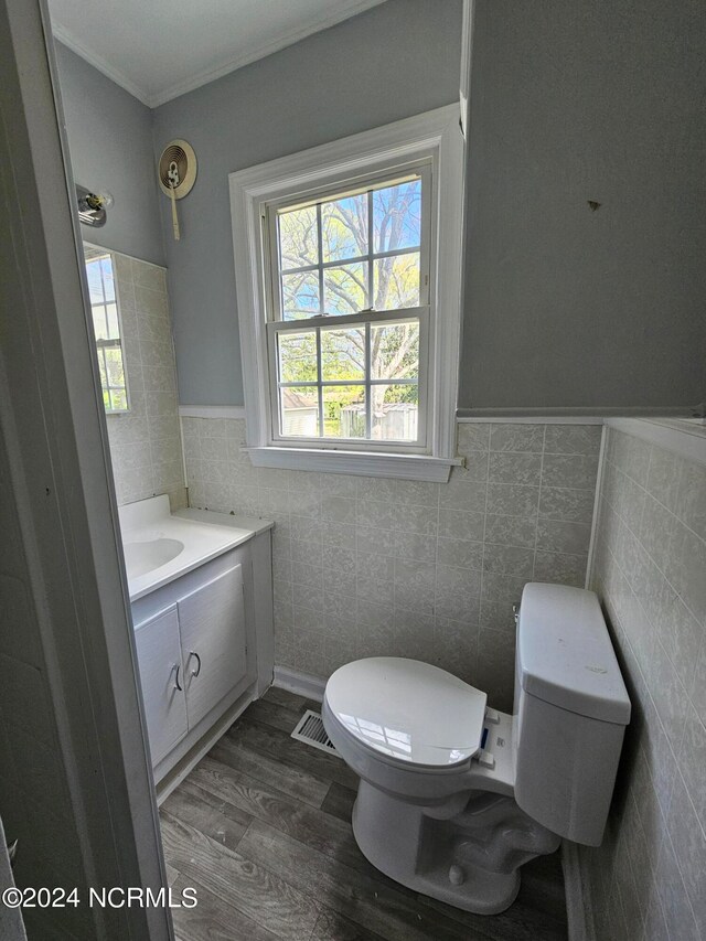 bathroom featuring toilet, tile walls, ornamental molding, wood-type flooring, and vanity