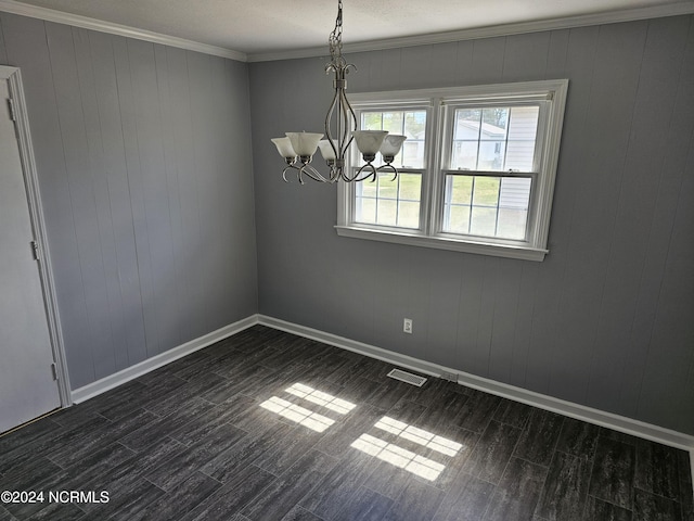 unfurnished dining area with dark hardwood / wood-style floors, crown molding, and a chandelier