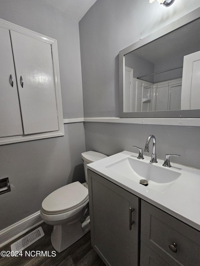 bathroom featuring toilet, vanity, wood-type flooring, and walk in shower