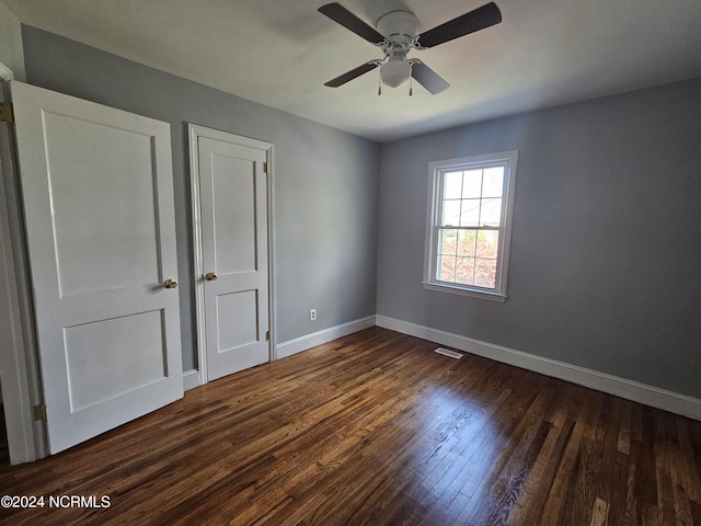 unfurnished bedroom with ceiling fan and dark hardwood / wood-style flooring