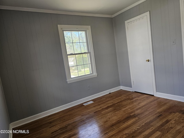 spare room with ornamental molding and dark hardwood / wood-style floors