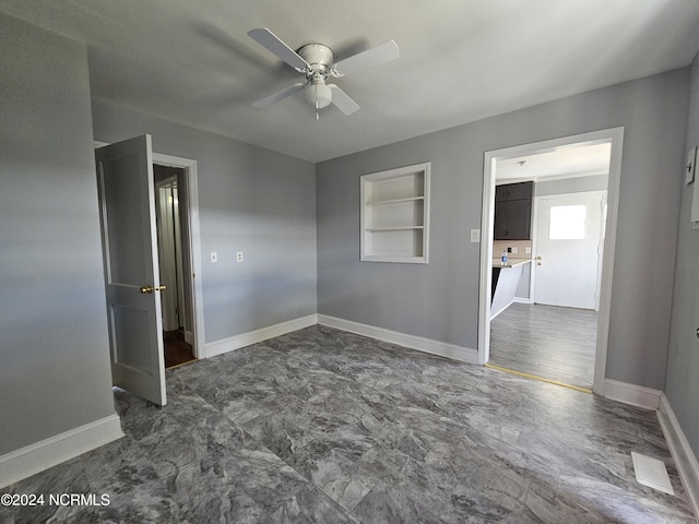 empty room with built in features and ceiling fan