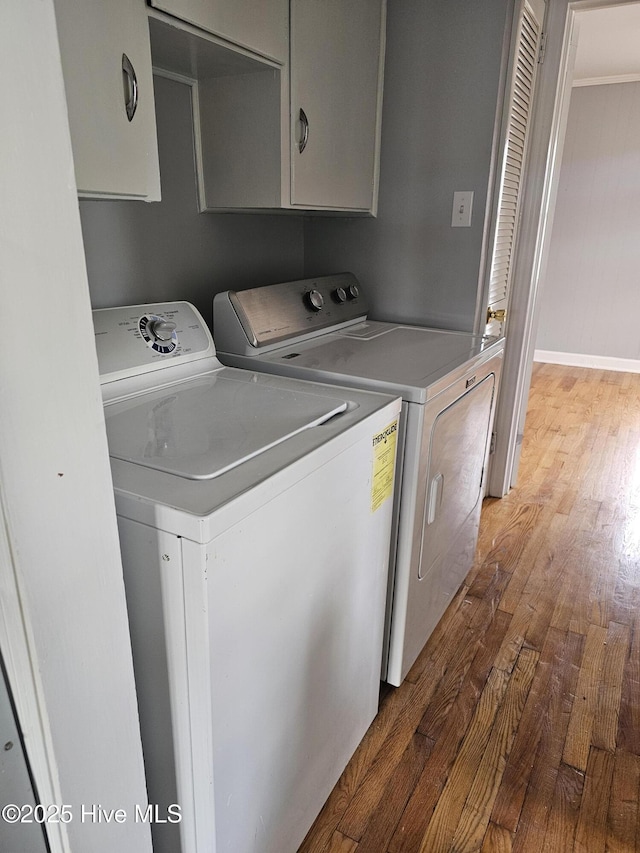 laundry area featuring washing machine and dryer, cabinets, and hardwood / wood-style floors