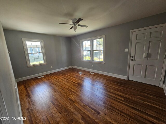 spare room featuring ceiling fan, dark hardwood / wood-style floors, and a healthy amount of sunlight