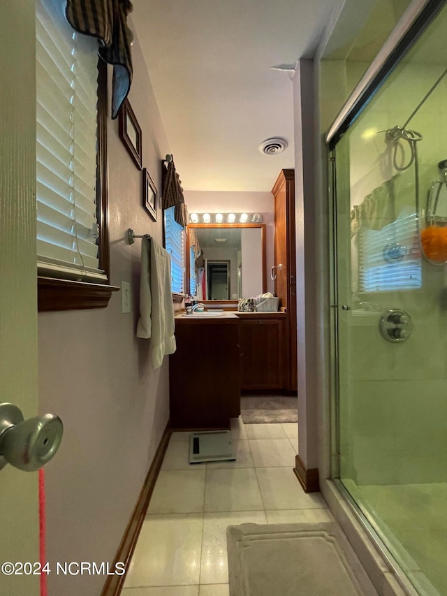 bathroom with oversized vanity, tile flooring, and a shower with door