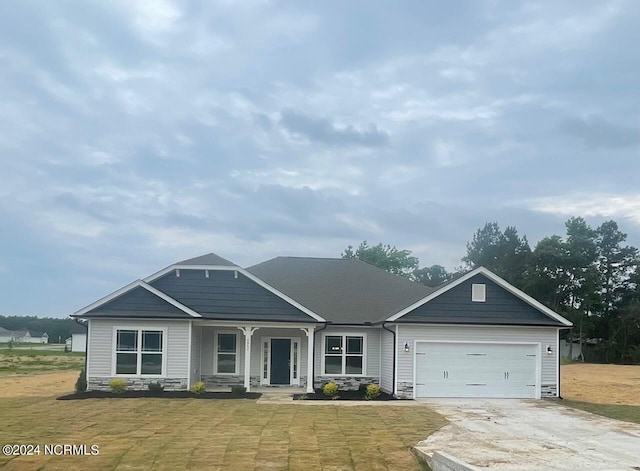 view of front facade featuring a front lawn, a garage, and covered porch