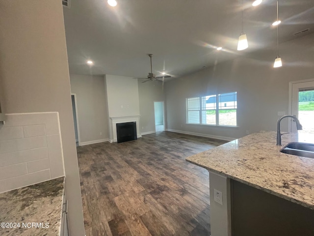 kitchen with hanging light fixtures, light stone countertops, dark hardwood / wood-style flooring, sink, and ceiling fan