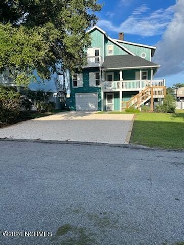 view of front of house with stairs, driveway, a front lawn, and a garage