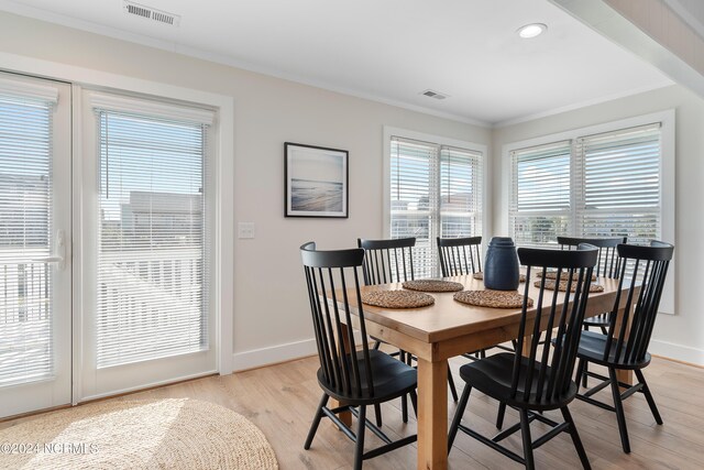 dining room with crown molding and light hardwood / wood-style flooring