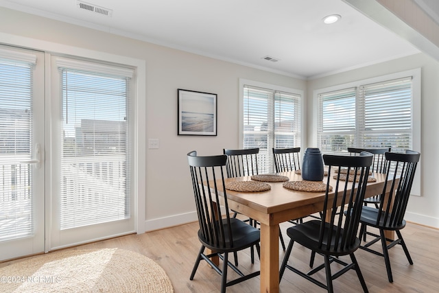 dining space featuring baseboards, light wood-style flooring, visible vents, and crown molding