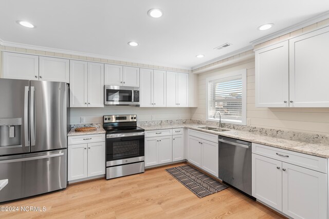 kitchen featuring crown molding, stainless steel appliances, sink, white cabinets, and light hardwood / wood-style floors